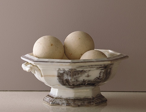 A decorative rustic bowl against a painted wall in Smoked Oyster 2109-40.