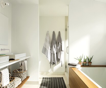Une salle de bains recouverte de Dentelle Délicate OC-65 présente un bain en bois et un petit tapis rayé.