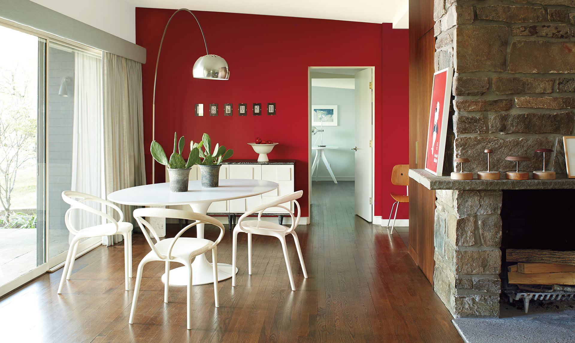 A contemporary dining room features a bold red accent wall with modern furnishings and fixtures.