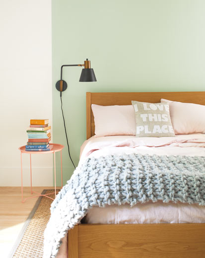 A bed set against a light green feature wall