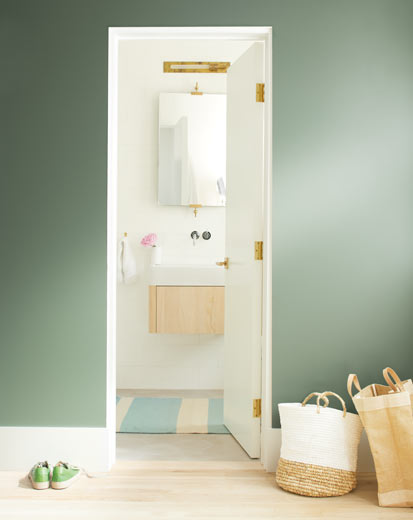 A dark green wall leads to a bright, neutral bathroom