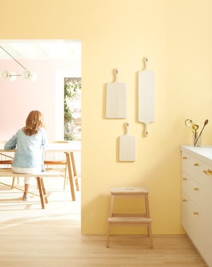 Une cuisine pâle aux murs jaune clair et aux armoires blanches