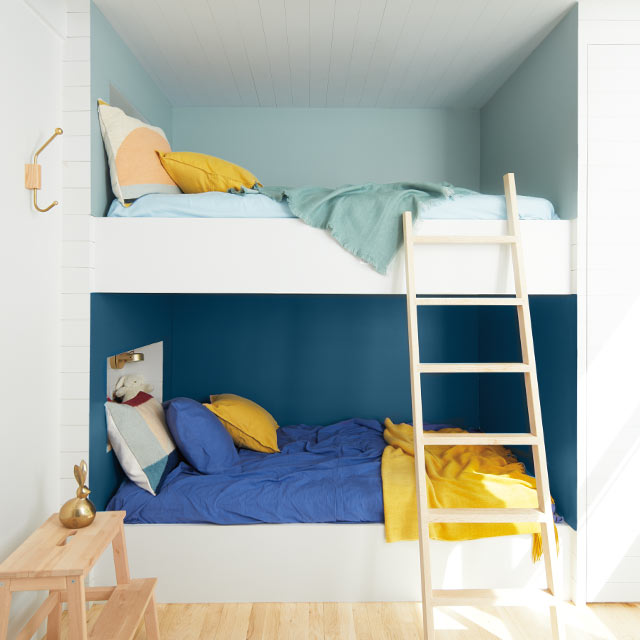 Des lits superposés dans une alcôve aux murs en deux teintes de bleu