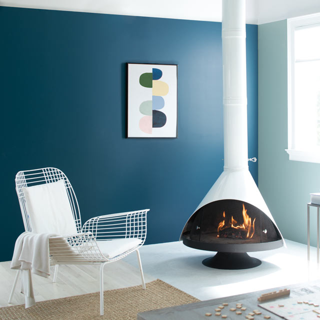 Una sala de estar acogedora se completa con una chimenea retro acompañada por paredes pintadas de azul Una sala de estar acogedora se completa con una chimenea retro acompañada por paredes pintadas de azul