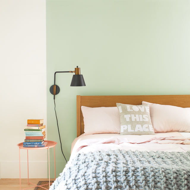 Una cama apoyada contra una pared destacada en verde claro Una cama apoyada contra una pared destacada en verde claro