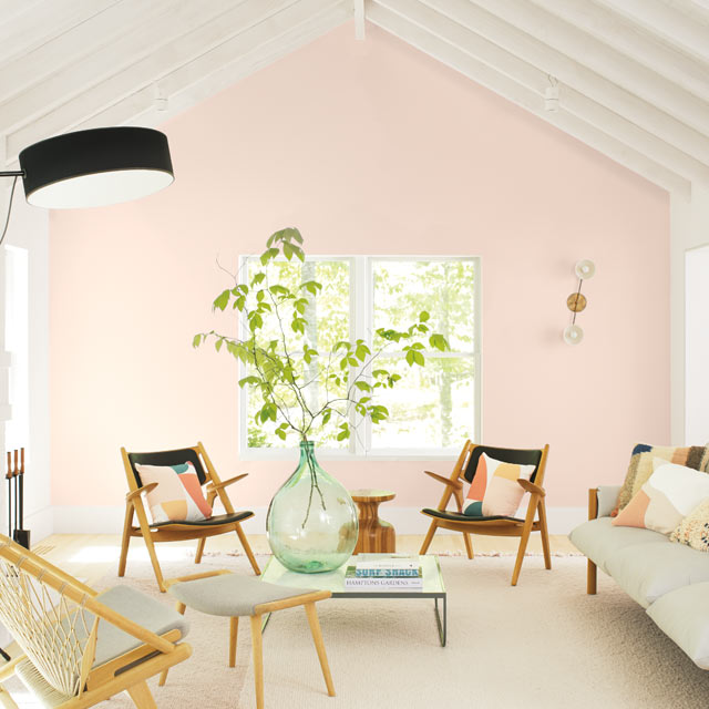 Un salon au style décontracté présente un mur d’accent rose pâle