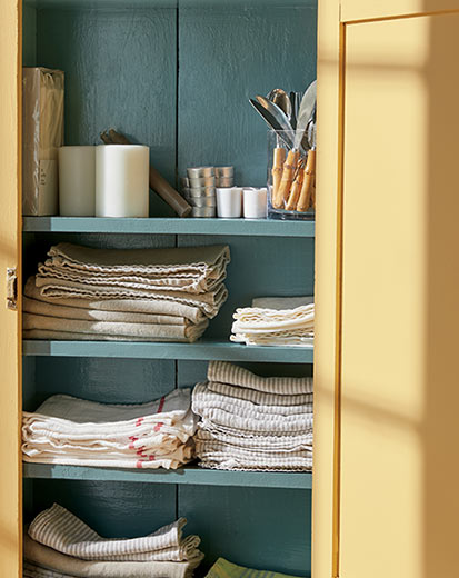 An open linen cabinet painted in Chestertown Buff HC-9 and Aegean Teal 2136-40.