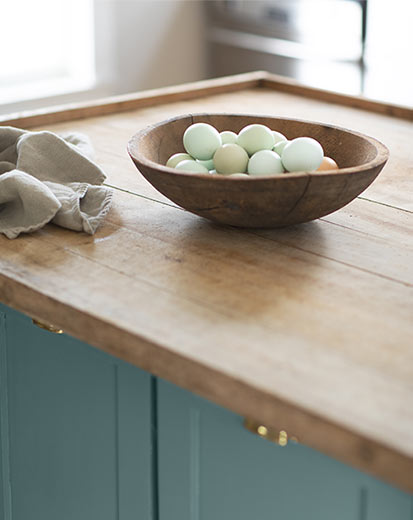 A kitchen island with a wooden countertop and cabinets painted Aegean Teal 2136-40.