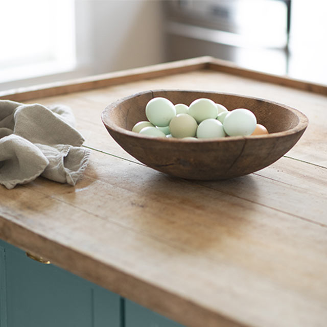 A kitchen island with a wooden countertop and cabinets painted Aegean Teal 2136-40.