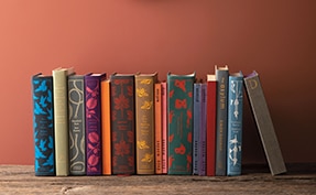 Books on a shelf under a hanging mirror, and wall painted in Rosy Peach 2089-20.