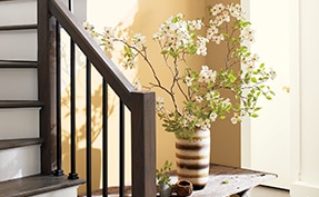 A staircase with wooden railings, white risers, and walls painted in Chestertown Buff HC-9.