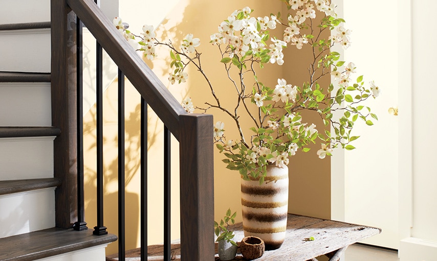 A staircase with wooden railings, white risers, and walls painted in Chestertown Buff HC-9.