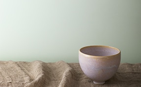 A clay bowl on a countertop in front of a wall painted in Gray Cashmere 2138-60.