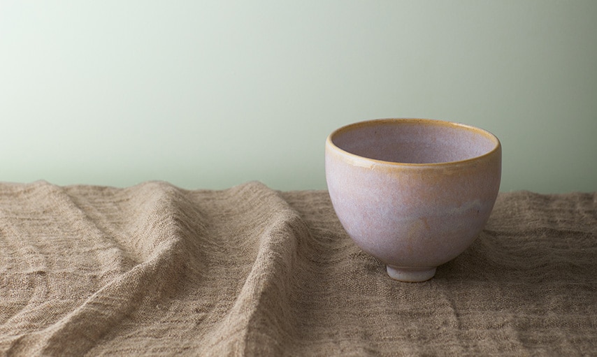 A clay bowl on a countertop in front of a wall painted in Gray Cashmere 2138-60.