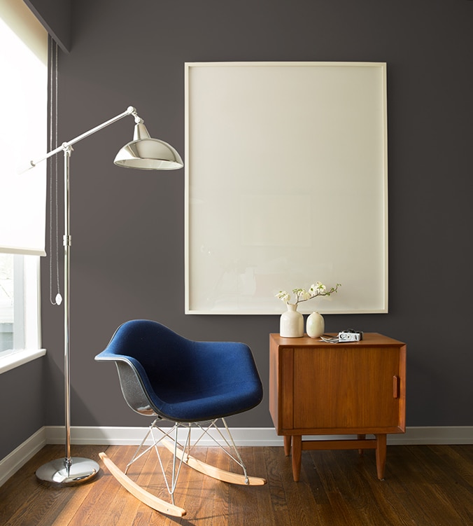 Un fauteuil berçant bleu, une table d’appui moderne des années 1950 et une lampe chromée sur pied de style contemporain agrémentent le coin de cette pièce.