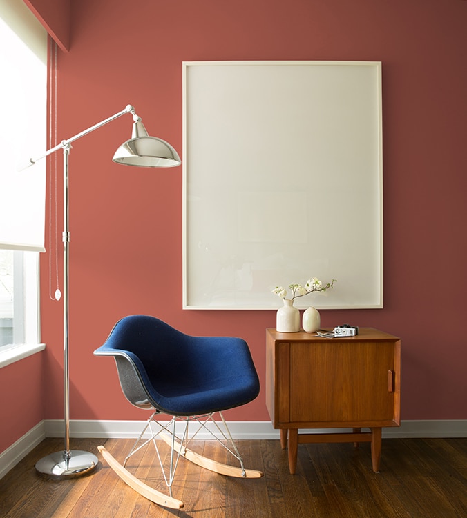 Un fauteuil berçant bleu, une table d’appui moderne des années 1950 et une lampe chromée sur pied de style contemporain agrémentent le coin de cette pièce.