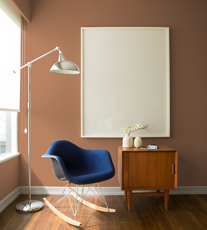 Un fauteuil berçant bleu, une table d’appui moderne des années 1950 et une lampe chromée sur pied de style contemporain agrémentent le coin de cette pièce.