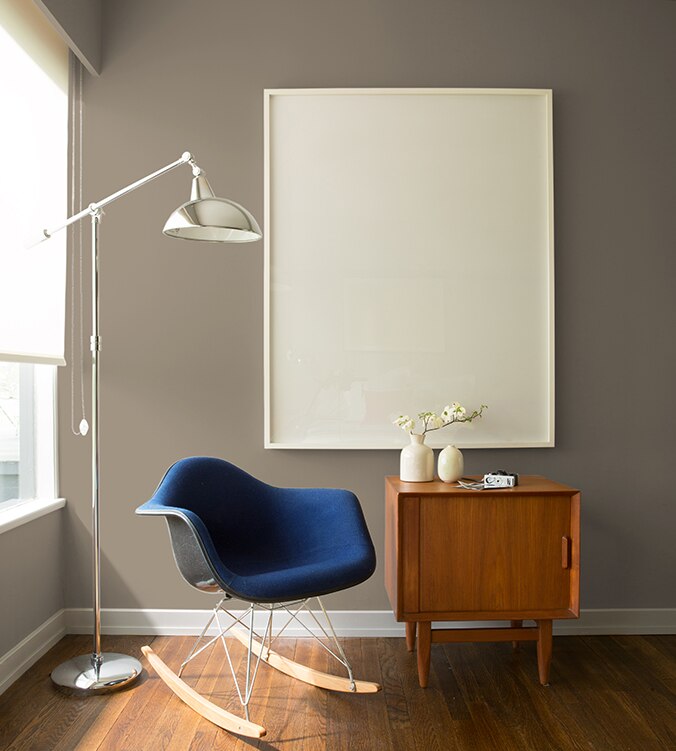 Un fauteuil berçant bleu, une table d’appui moderne des années 1950 et une lampe chromée sur pied de style contemporain agrémentent le coin de cette pièce.