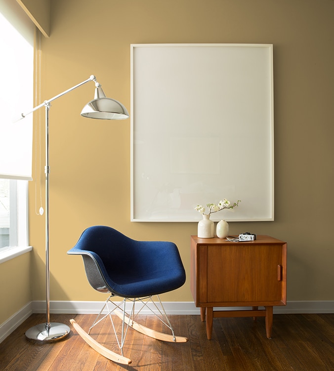 Un fauteuil berçant bleu, une table d’appui moderne des années 1950 et une lampe chromée sur pied de style contemporain agrémentent le coin de cette pièce.