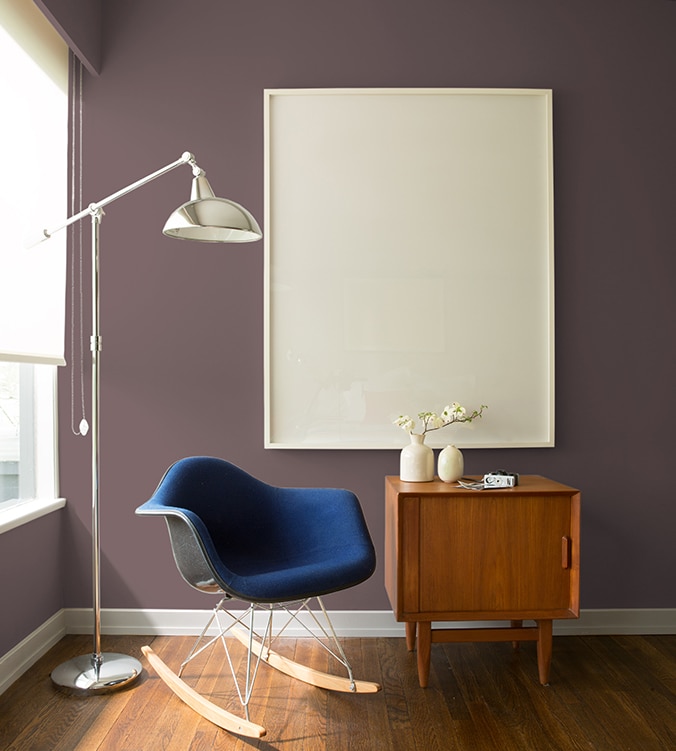 Un fauteuil berçant bleu, une table d’appui moderne des années 1950 et une lampe chromée sur pied de style contemporain agrémentent le coin de cette pièce.