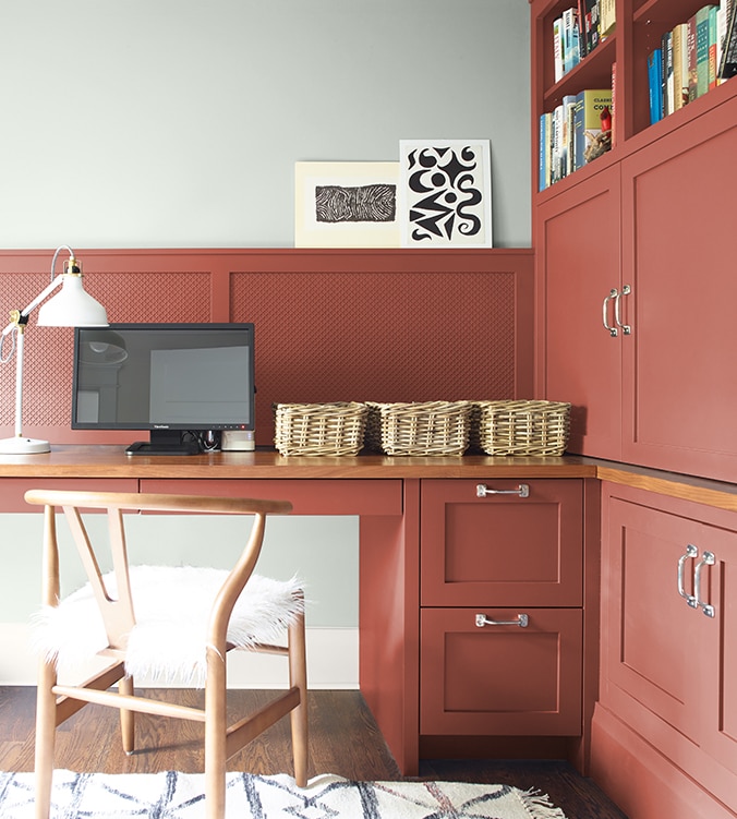 Coin-bureau avec table de travail encastrée, armoires et étagères, chaise en bois doré et lampe de bureau blanche.