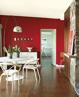 A contemporary dining room features a bold red accent wall with modern furnishings and fixtures.