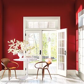 Un boudoir aux murs rouge vif baigne dans la lumière qui entre par plusieurs portes-fenêtres blanches. Un boudoir aux murs rouge vif baigne dans la lumière qui entre par plusieurs portes-fenêtres blanches.