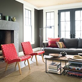 Salon dont les murs gris sont accentués par des chaises d’un rouge éclatant. Salon dont les murs gris sont accentués par des chaises d’un rouge éclatant.