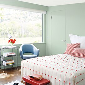 Chambre à coucher lumineuse et confortable avec petit tabouret rouge au pied du lit à la literie colorée et ludique. Chambre à coucher lumineuse et confortable avec petit tabouret rouge au pied du lit à la literie colorée et ludique.