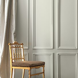 A gray-painted wall and cream-coloured silk curtains frame a formal gold chair. A gray-painted wall and cream-coloured silk curtains frame a formal gold chair.