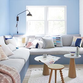 Light blue living room walls frame a large gray banquette. Light blue living room walls frame a large gray banquette.