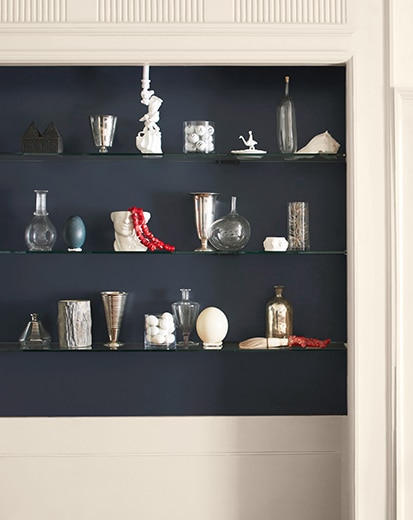 White wall with dark-blue inset shelving and backsplash featuring a variety of décor.