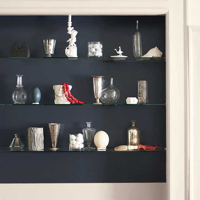 White wall with dark-blue inset shelving and backsplash featuring a variety of décor.