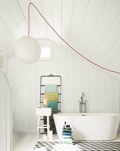 Une salle de bains blanche avec une suspension sphérique, une grande baignoire, des étagères noires, un plafond en planches à feuillure et un tabouret-escabeau blanc.