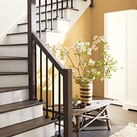 A staircase with wooden railings, white risers, and walls painted in Chestertown Buff HC-9. A staircase with wooden railings, white risers, and walls painted in Chestertown Buff HC-9.
