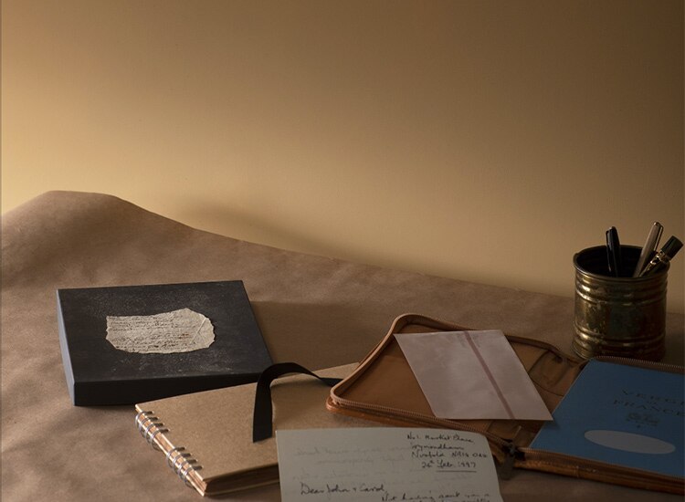 Journals and a can of pencils and pens sitting on a piece of fabric in a beige room. Join the List