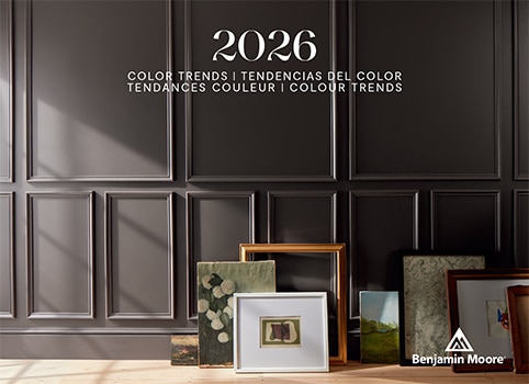 Artwork and frames arranged on a floor against a deep chocolate brown-painted wall with decorative moulding. Artwork and frames arranged on a floor against a deep chocolate brown-painted wall with decorative moulding.