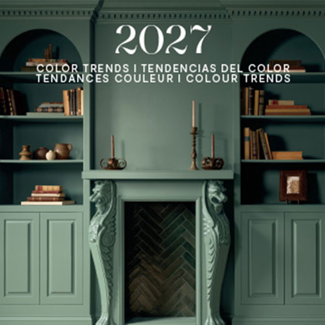 A green painted room with lower paneled walls and arched, built-in shelving topped with books and decor.