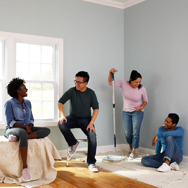 Four young adult friends gather in a room that they are painting.