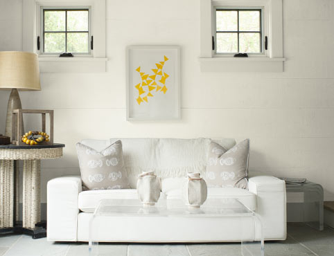 Una sala de estar luminosa con paredes traslapadas blancas realzadas con muebles y accesorios neutros. Una sala de estar luminosa con paredes traslapadas blancas realzadas con muebles y accesorios neutros.
