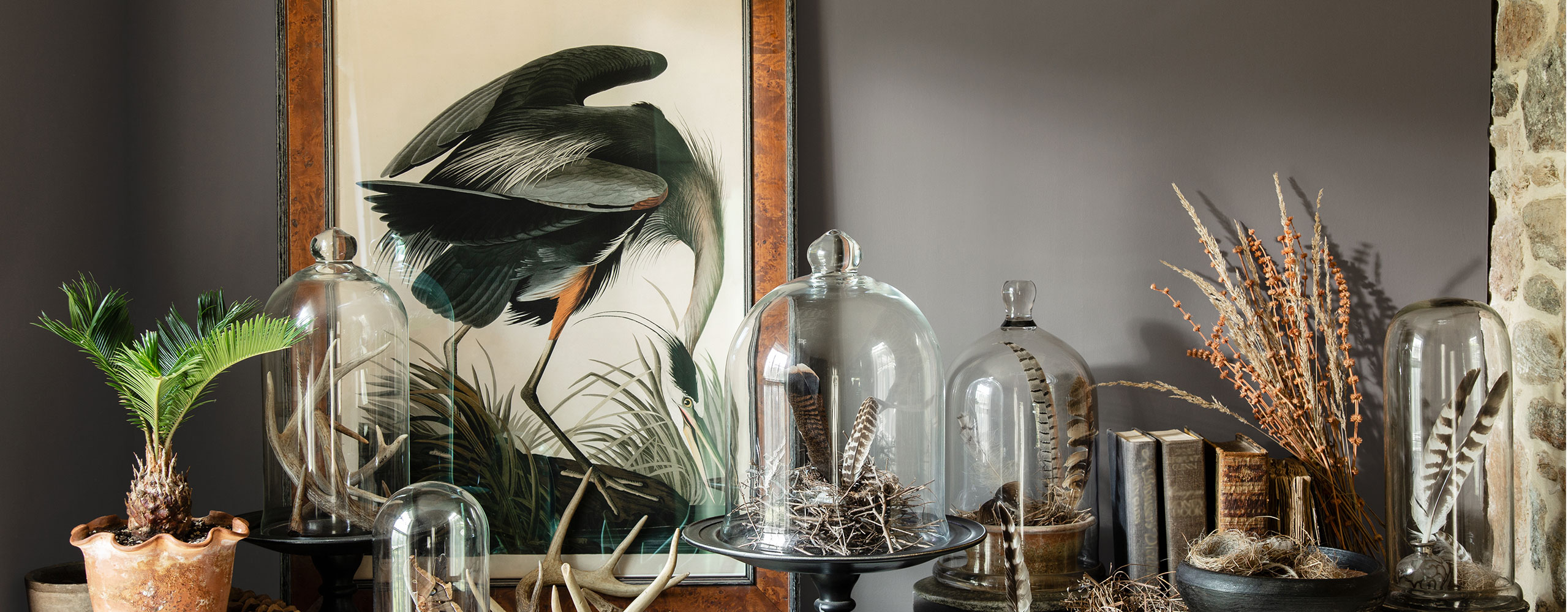 A stone shelf featuring autumnal flora and fauna against a deep gray-painted wall.