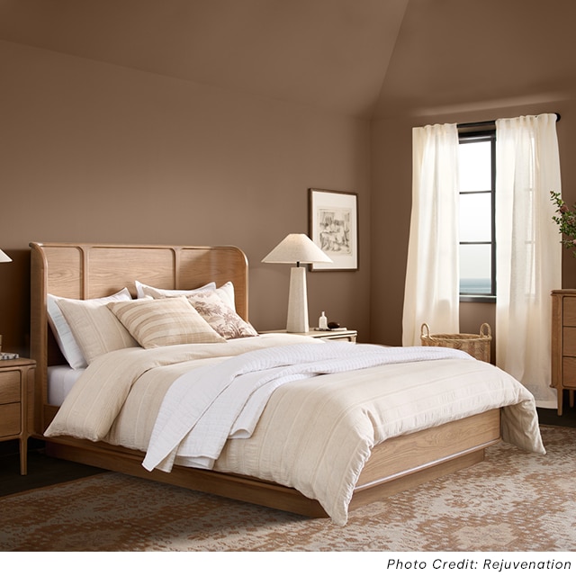 A spacious light brown-painted bedroom with a vaulted ceiling and neutral, modern decor.