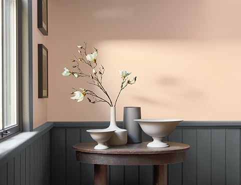 A light peach-painted room contrasted by dark gray wainscoting.