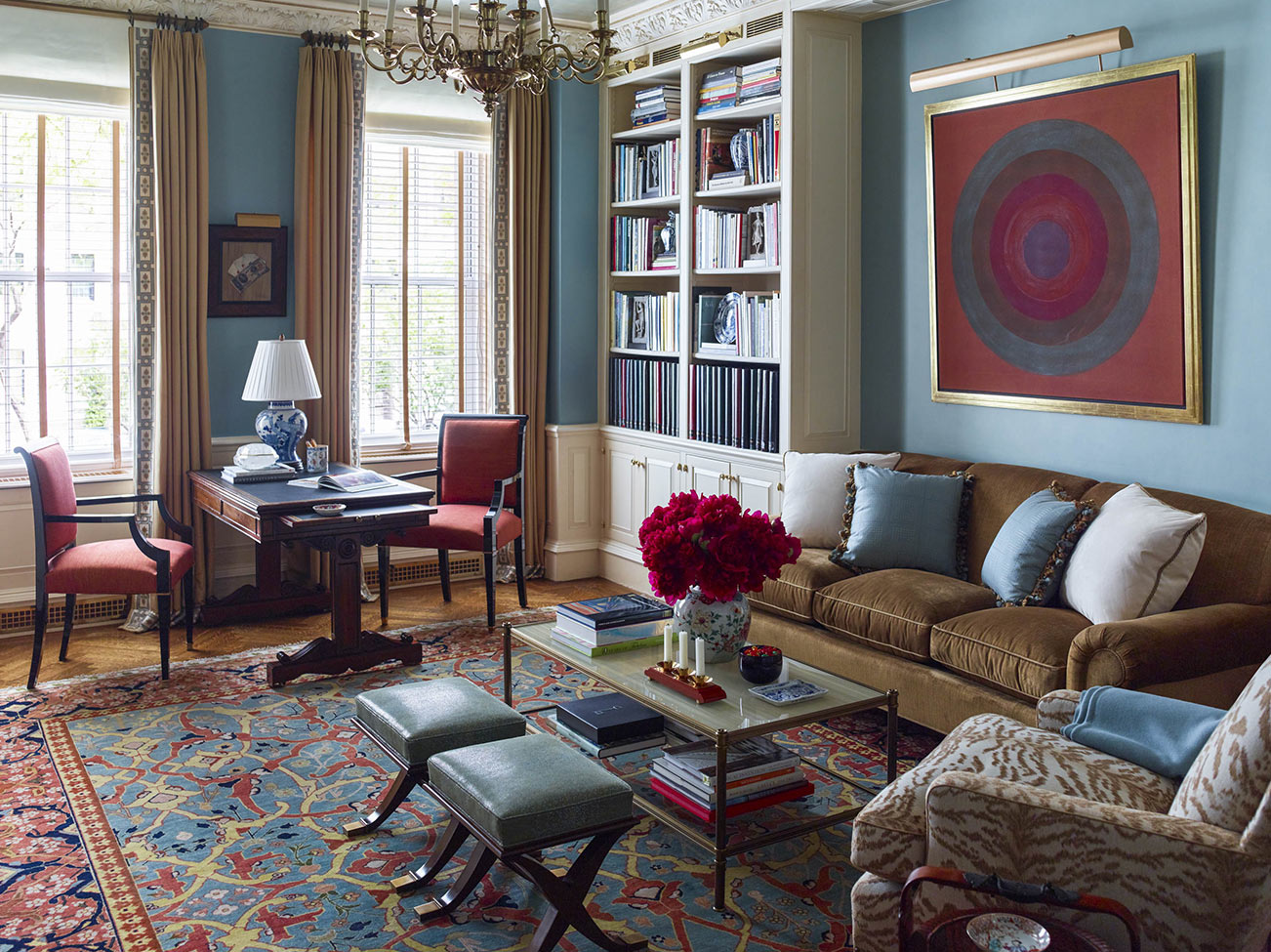 Classic NYC apartment living room with painted blue walls, luxuriously upholstered furniture, and multi-coloured woven area rug.