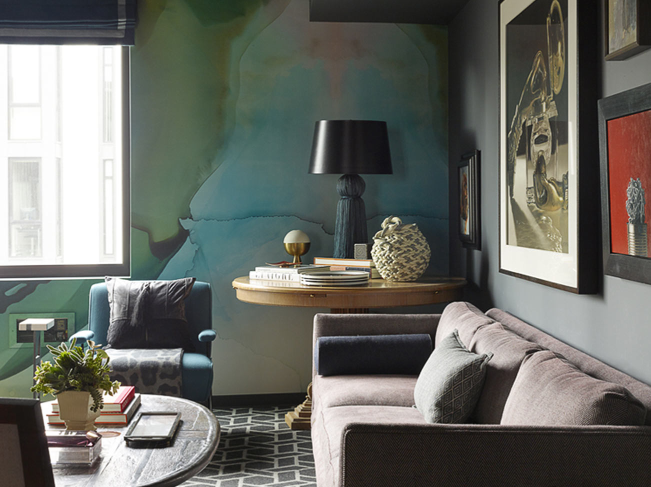 Living room with walls in blue-green blended paint, gray velvet tuxedo sofa, and assorted wall art.
