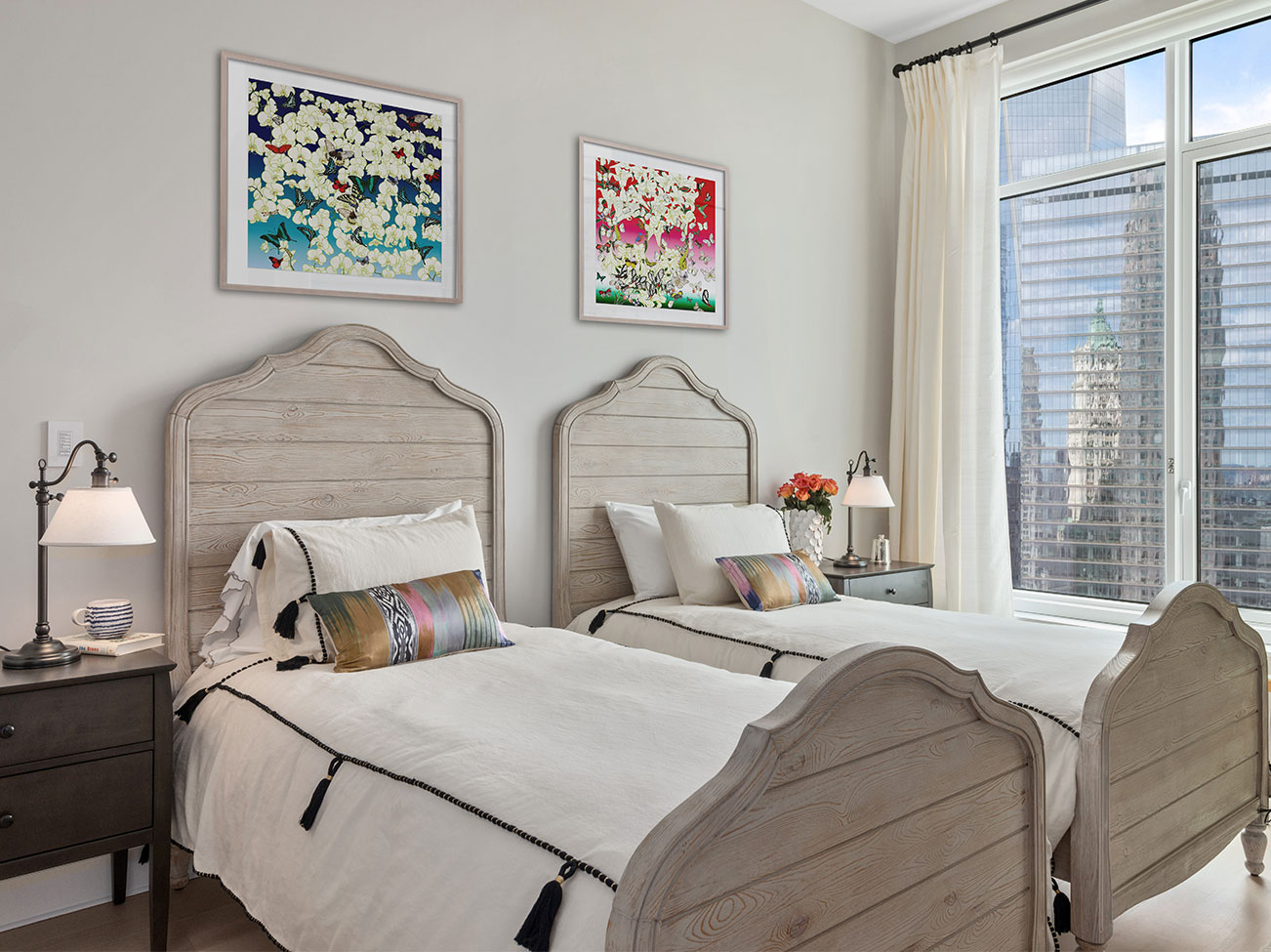 Bedroom with twin beds artwork over headboards, pale gray walls, city view through sheer shades and white curtains. Bedroom with twin beds artwork over headboards, pale gray walls, city view through sheer shades and white curtains.