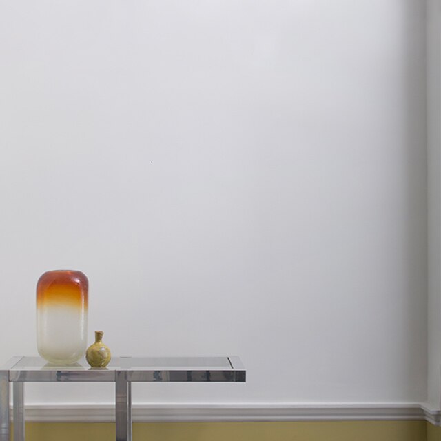 Off-white walls with yellow trim, modern end table and mobile on the ceiling.