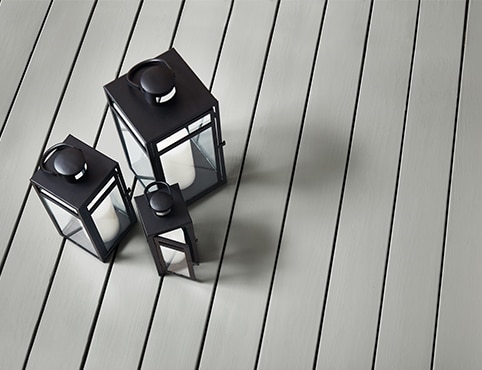 Three black lanterns on a deck stained with Platinum Gray HC-179 Ultra Flat Solid Woodluxe® Exterior Stain.