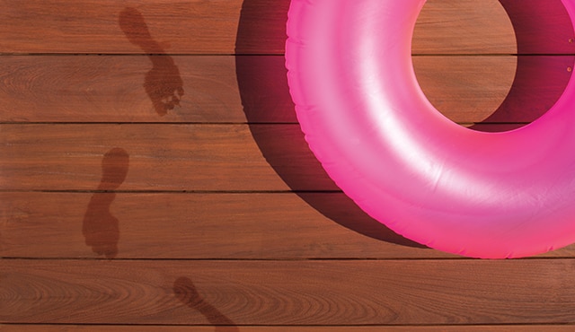 A stained deck with pink pool tube on it, and wet footprints. A stained deck with pink pool tube on it, and wet footprints.