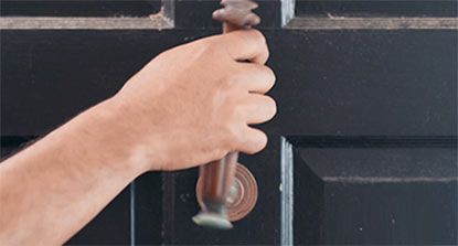 An image of a person removing hardware from an exterior door in preparation for painting.